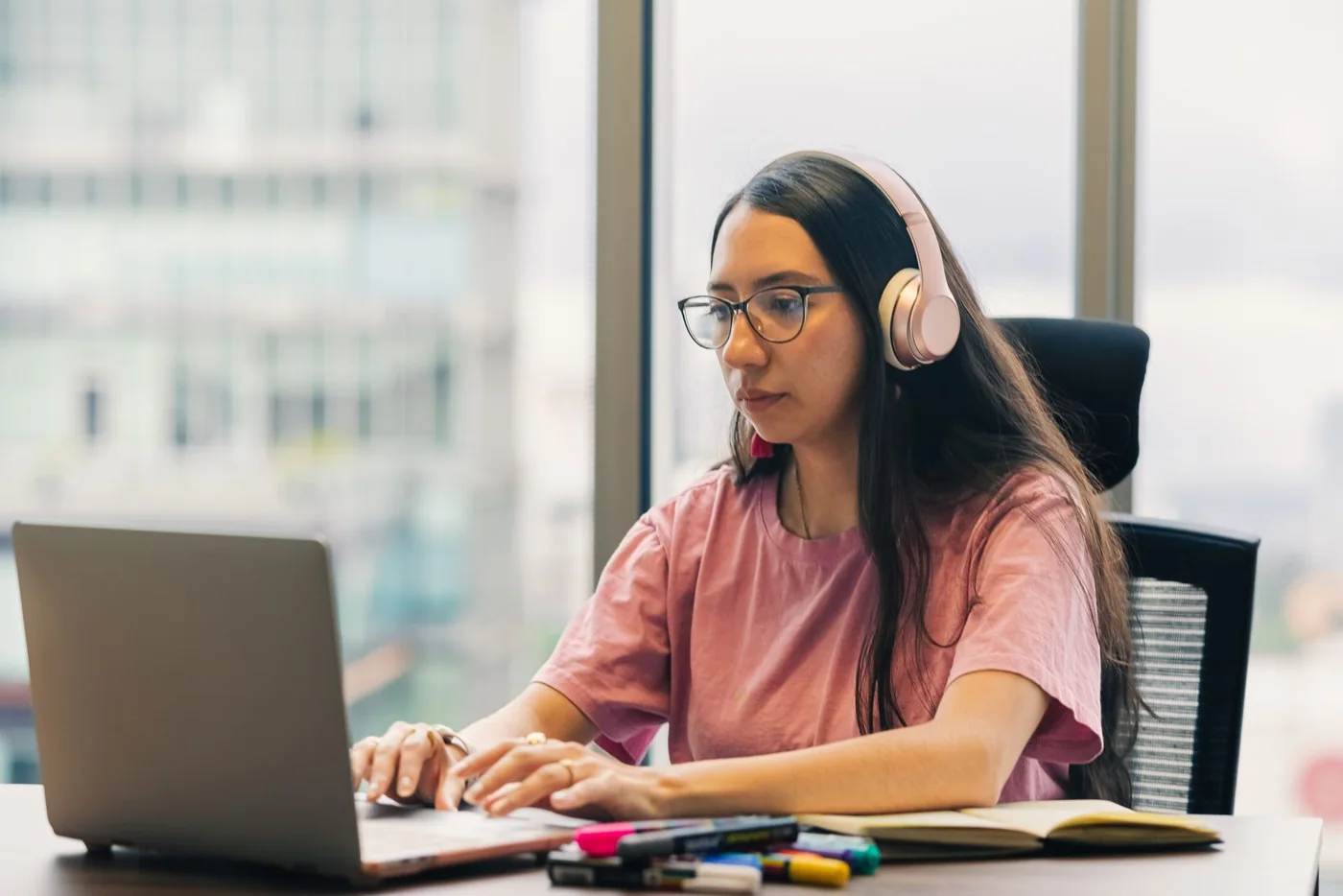 A professional reviewing work on a laptop while wearing headphones