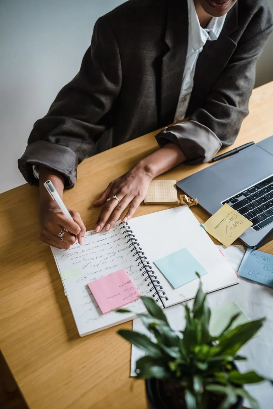 Hands taking planning notes beside a laptop and sticky notes