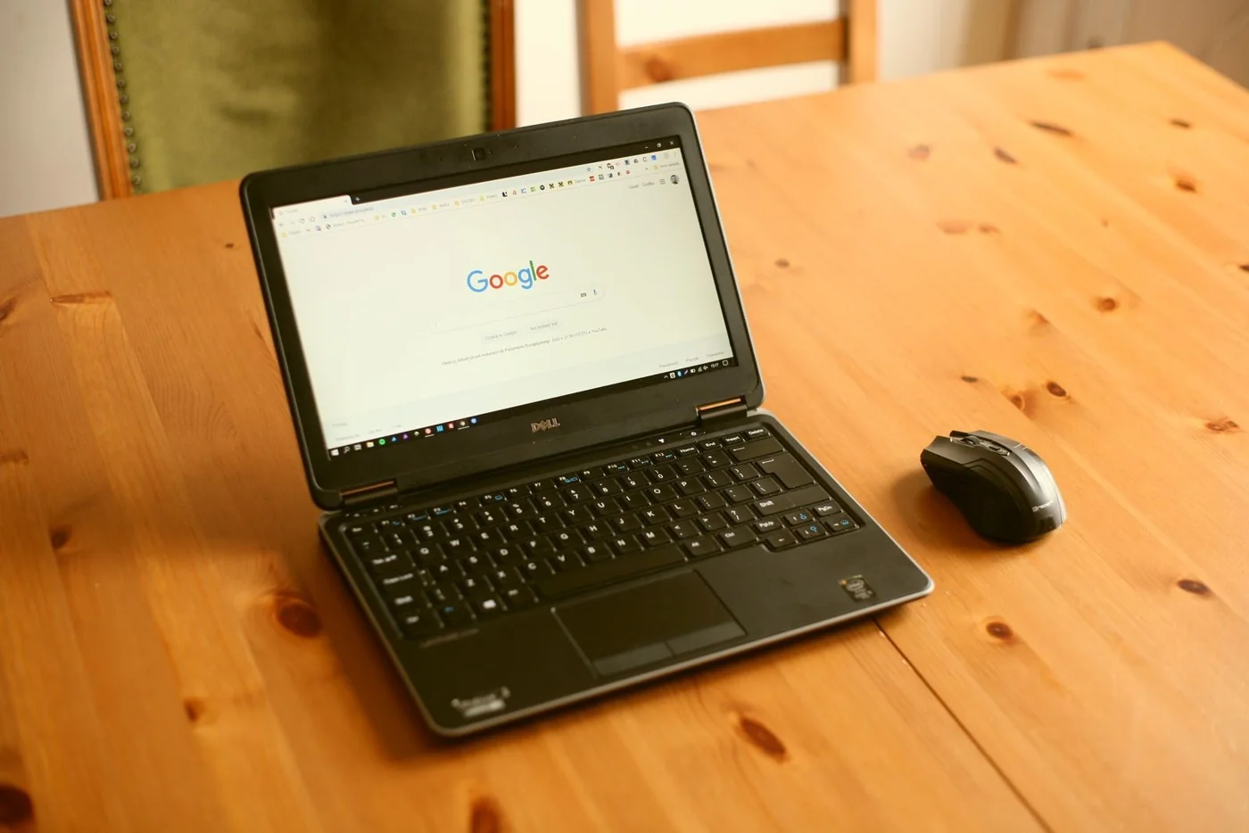 A laptop displaying Google search beside a wireless mouse
