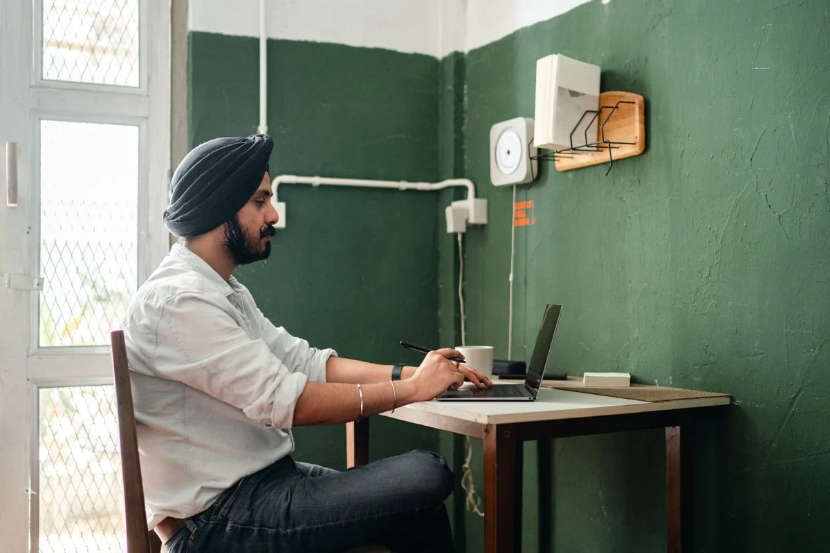 An Indian professional writing notes beside his laptop