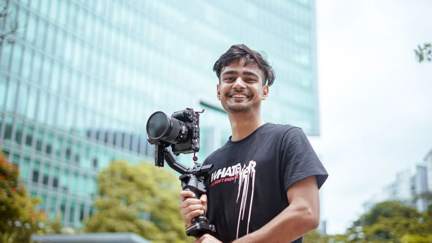 An Indian filmmaker holding a camera and stabilizer on location
